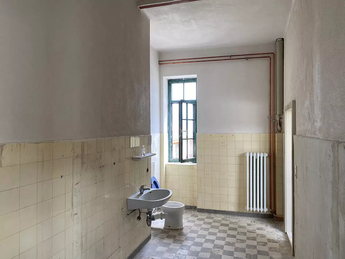 Unsanierter Sanitärraum mit alter Fliesenverkleidung vor dem Umbau